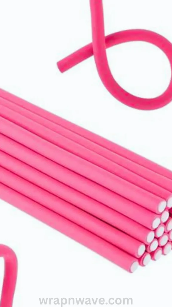 A close-up product shot of bright pink foam flexi rods against a plain white background. A bundle of straight pink rods is stacked neatly together, showing their soft foam exterior and white inner core ends, while one rod above is bent into a loose loop to demonstrate its flexible, soft design for comfortable overnight wear. The text "wrapnwave.com" is watermarked in grey at the bottom.