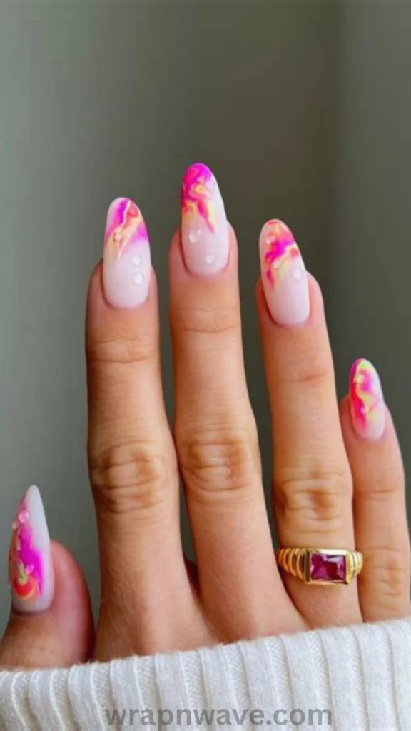Close-up of long, oval-shaped nails with a milky, pale pink base and vibrant marble swirl art on the tips featuring magenta pink, bright yellow, and lime green accents, finished with clear water droplet embellishments.